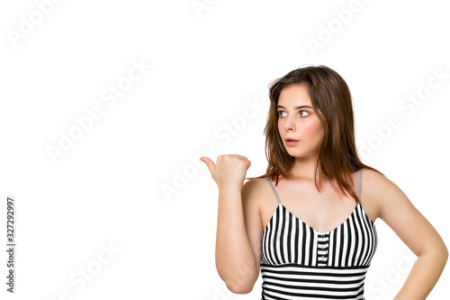 Young brunette looking surprised shows back in disbelief, saying wow, unbelievable on white background