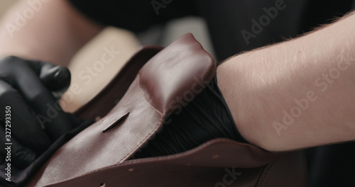 man hands in black gloves applying protective cream to brown leather sneakers © GCapture