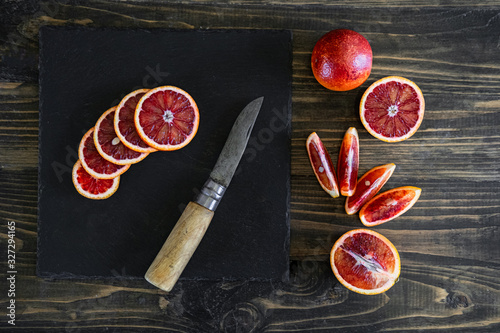 sliced sicilian or bloody oranges on a black slate background 