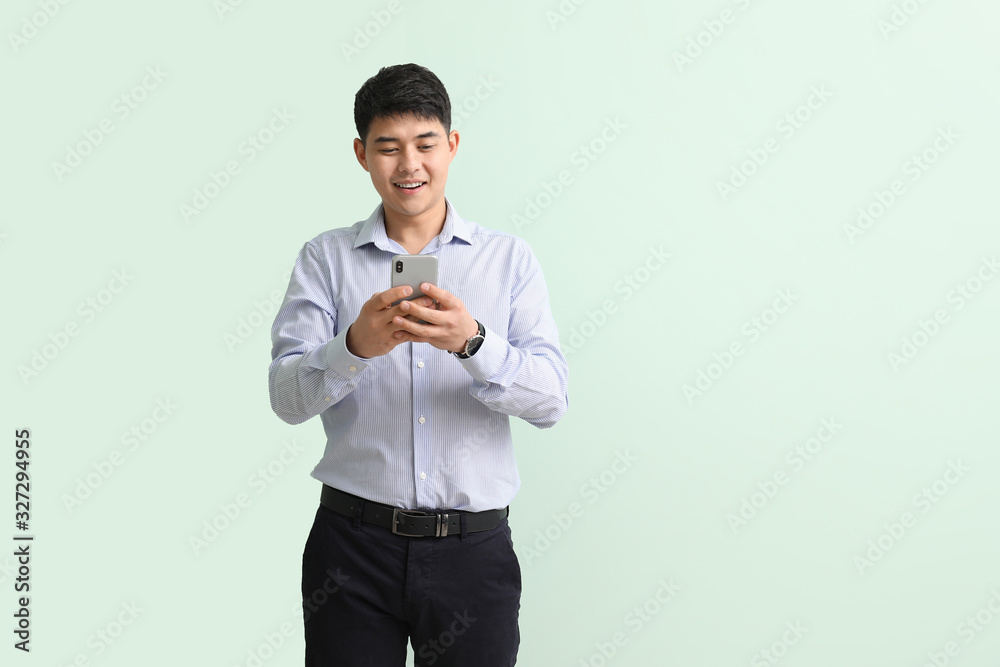 Young Asian businessman with mobile phone on color background Young Asian businessman with mobile phone on color background