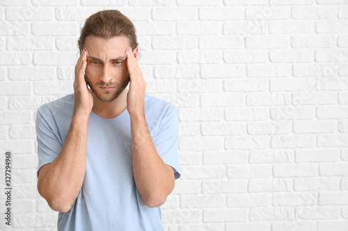 Portrait of worried young man near white brick wall