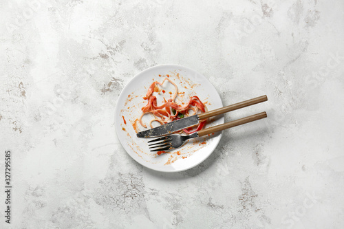 Dirty empty plate with cutlery on light background