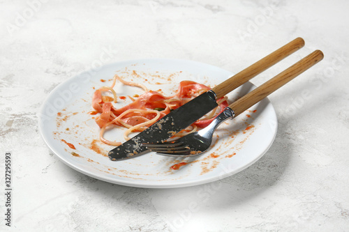 Dirty empty plate with cutlery on light background