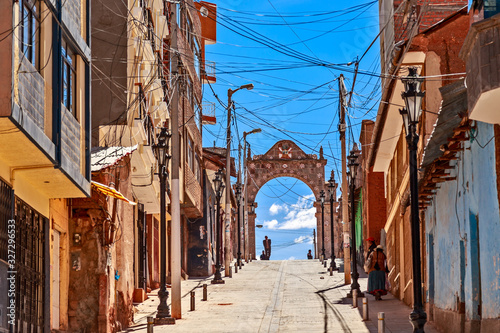 Wired streets of Puno with colonial Spanish arch in background, Peru photo