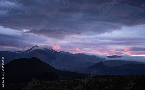 Mountain peak with snow and clouds during dramatic and colorful sunset
