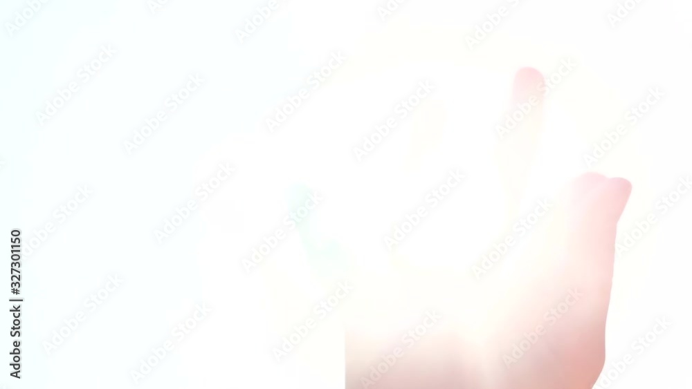 Summer rays of sunlight shine through child’s hand, close-up. Sunbeams on child’s fingers on bright sky background. Summer rays of sunlight shine through child’s hand, close-up. Sunbeams on child’s fingers on bright sky background.