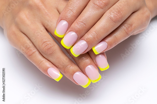 yellow french manicure, sparkles on short square nails closeup on a white background photo