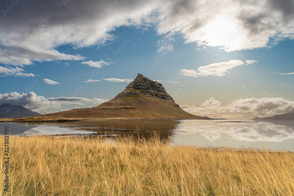 Kirkjufell in Iceland famous mountain reflecting in lake during calm sunny day