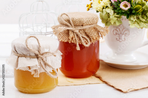 Jars with honey and bouquet of wild flowers on the table.
