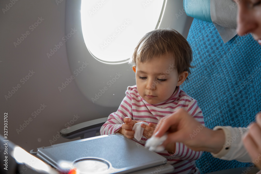 a little cute toddler girl sitting in an airplane in a chair by the
