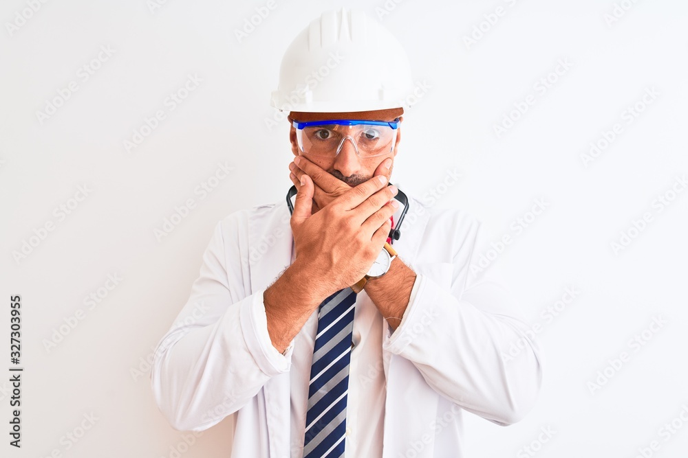 Young chemist man wearing security helmet and headphones over isolated background shocked covering mouth with hands for mistake. Secret concept. Young chemist man wearing security helmet and headphones over isolated background shocked covering mouth with hands for mistake. Secret concept.