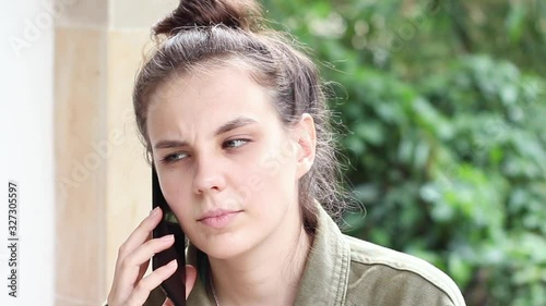 Young beautiful woman talking seriously on the phone outdoors