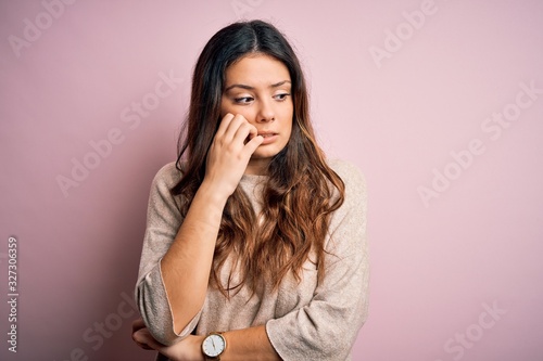 Foto Young beautiful brunette woman wearing casual sweater standing over pink background looking stressed and nervous with hands on mouth biting nails