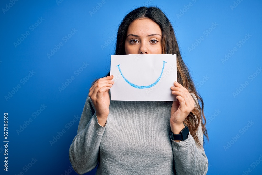 Young beautiful brunette positive woman holding card with smile emotion on mouth with a confident expression on smart face thinking serious Young beautiful brunette positive woman holding card with smile emotion on mouth with a confident expression on smart face thinking serious