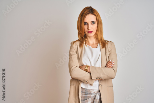 Redhead caucasian business woman standing over isolated background skeptic and nervous, disapproving expression on face with crossed arms. Negative person.