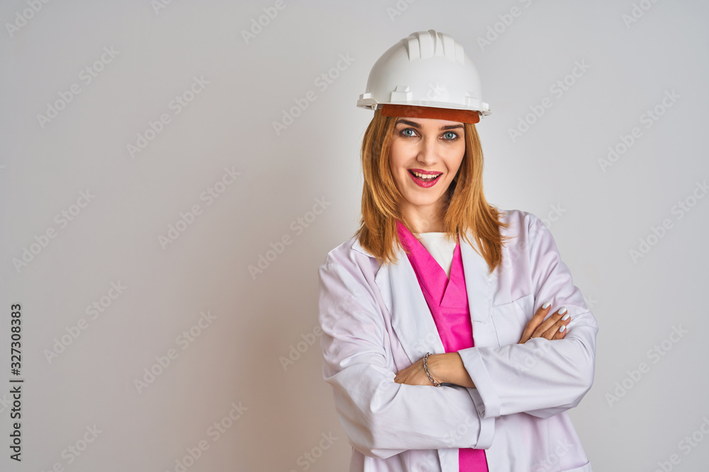 Redhead caucasian woman engineer wearing safety helmet over isolated background happy face smiling with crossed arms looking at the camera. Positive person. Redhead caucasian woman engineer wearing safety helmet over isolated background happy face smiling with crossed arms looking at the camera. Positive person.
