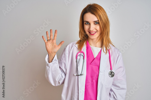 Redhead caucasian doctor woman wearing pink stethoscope over isolated background showing and pointing up with fingers number five while smiling confident and happy.