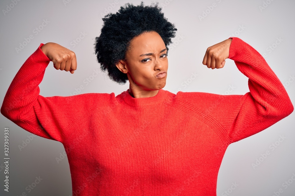 Young beautiful African American afro woman with curly hair wearing red casual sweater showing arms muscles smiling proud. Fitness concept. Young beautiful African American afro woman with curly hair wearing red casual sweater showing arms muscles smiling proud. Fitness concept.