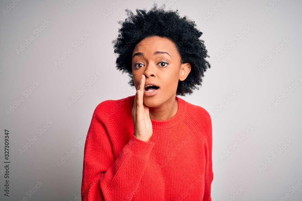 Young beautiful African American afro woman with curly hair wearing red casual sweater hand on mouth telling secret rumor, whispering malicious talk conversation Young beautiful African American afro woman with curly hair wearing red casual sweater hand on mouth telling secret rumor, whispering malicious talk conversation