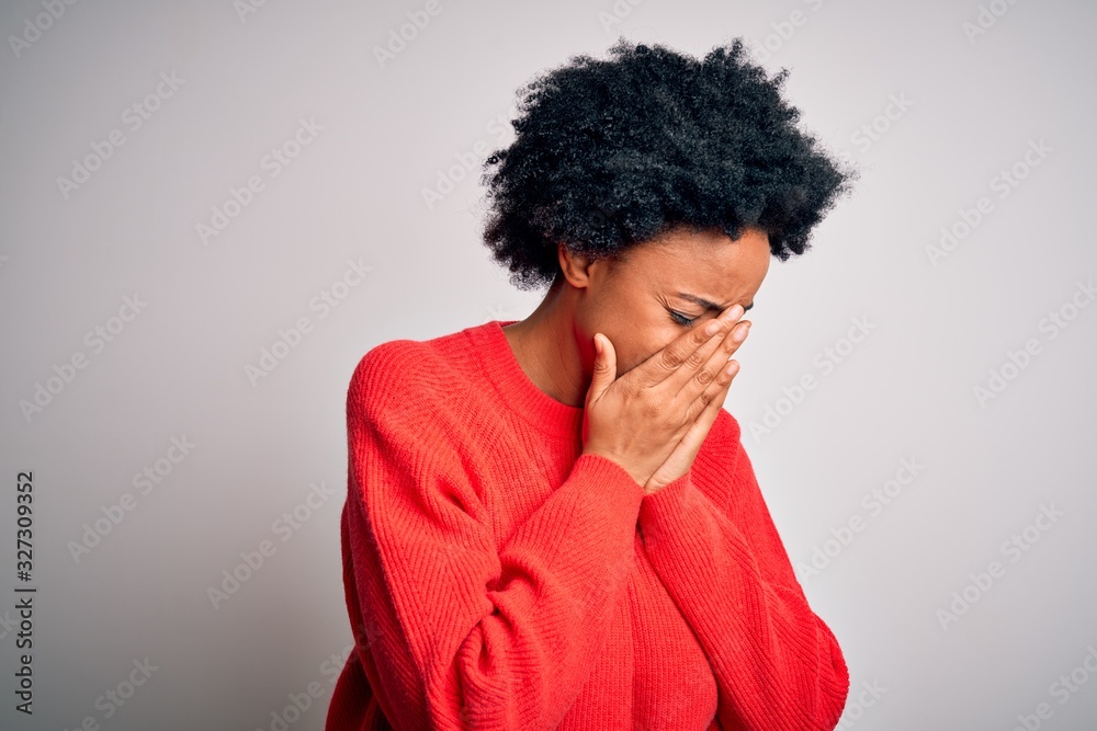 Young beautiful African American afro woman with curly hair wearing red casual sweater with sad expression covering face with hands while crying. Depression concept.