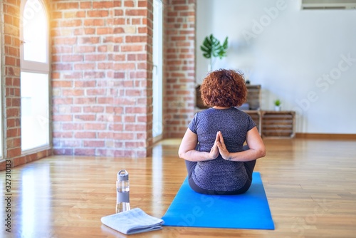 Tableau sur toile Middle age beautiful sportwoman sitting on mat on backview practicing yoga doing
