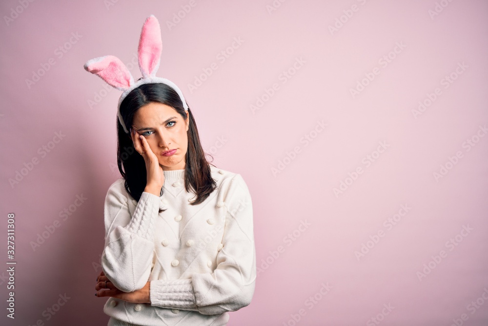 Young caucasian woman wearing cute easter rabbit ears over pink isolated background thinking looking tired and bored with depression problems with crossed arms.