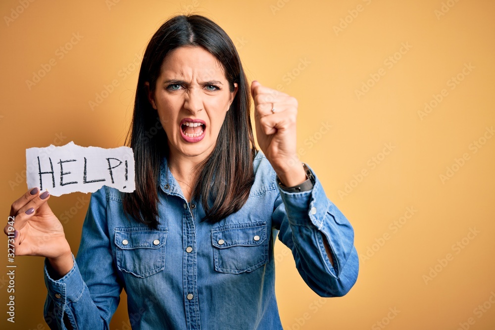 Young brunette woman with blue eyes holding for help and protection with help word text annoyed and frustrated shouting with anger, crazy and yelling with raised hand, anger concept Young brunette woman with blue eyes holding for help and protection with help word text annoyed and frustrated shouting with anger, crazy and yelling with raised hand, anger concept