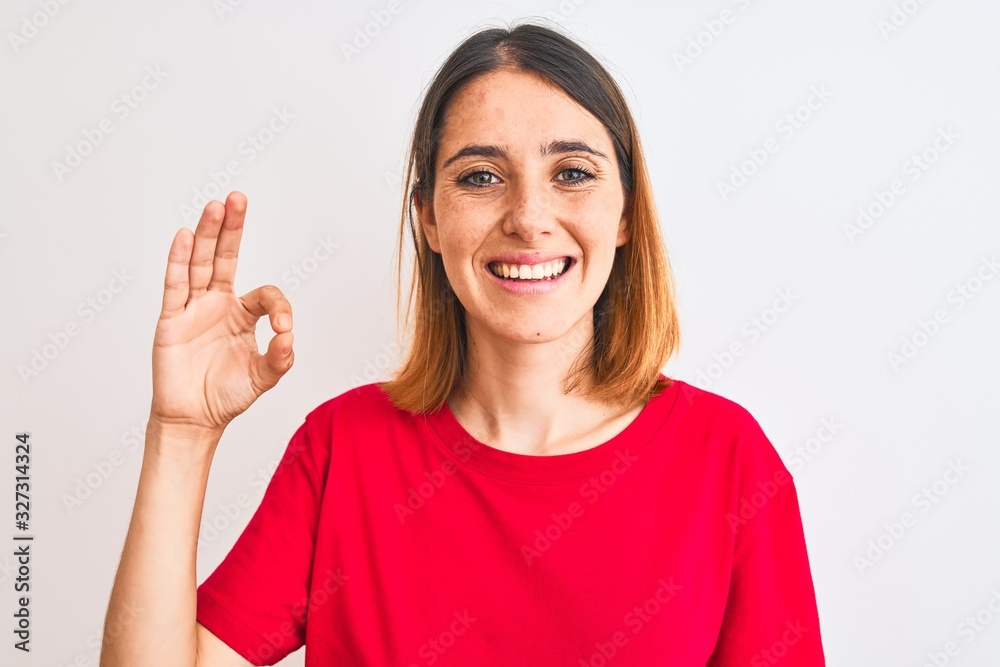 Beautiful redhead woman wearing casual red t-shirt over isolated background smiling positive doing ok sign with hand and fingers. Successful expression. Beautiful redhead woman wearing casual red t-shirt over isolated background smiling positive doing ok sign with hand and fingers. Successful expression.