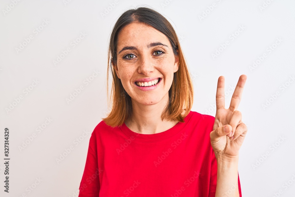 Beautiful redhead woman wearing casual red t-shirt over isolated background showing and pointing up with fingers number two while smiling confident and happy. Beautiful redhead woman wearing casual red t-shirt over isolated background showing and pointing up with fingers number two while smiling confident and happy.