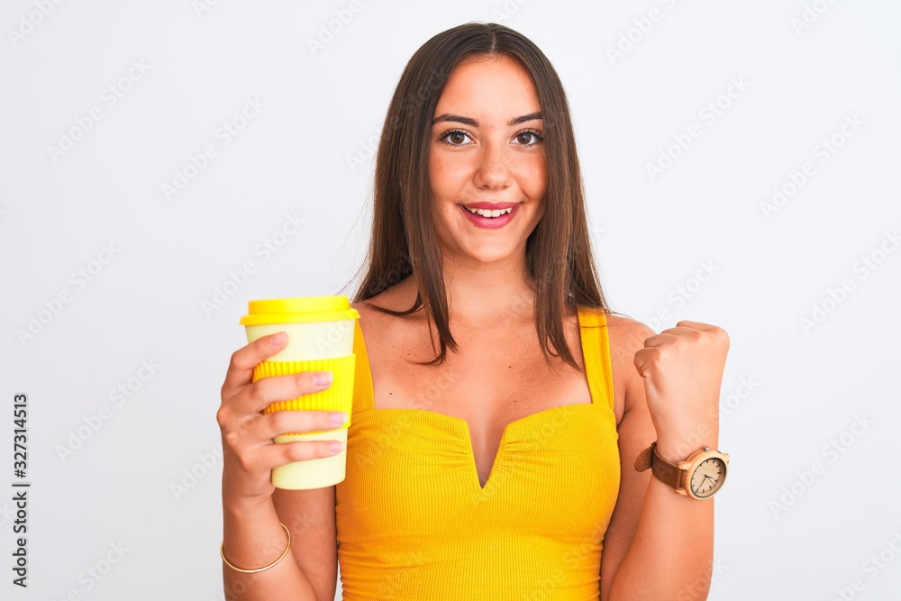 Young beautiful girl drinking paper glass of take away coffee over isolated white background screaming proud and celebrating victory and success very excited, cheering emotion Young beautiful girl drinking paper glass of take away coffee over isolated white background screaming proud and celebrating victory and success very excited, cheering emotion