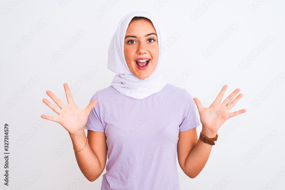 Young beautiful arabian girl wearing hijab standing over isolated white background celebrating crazy and amazed for success with arms raised and open eyes screaming excited. Winner concept