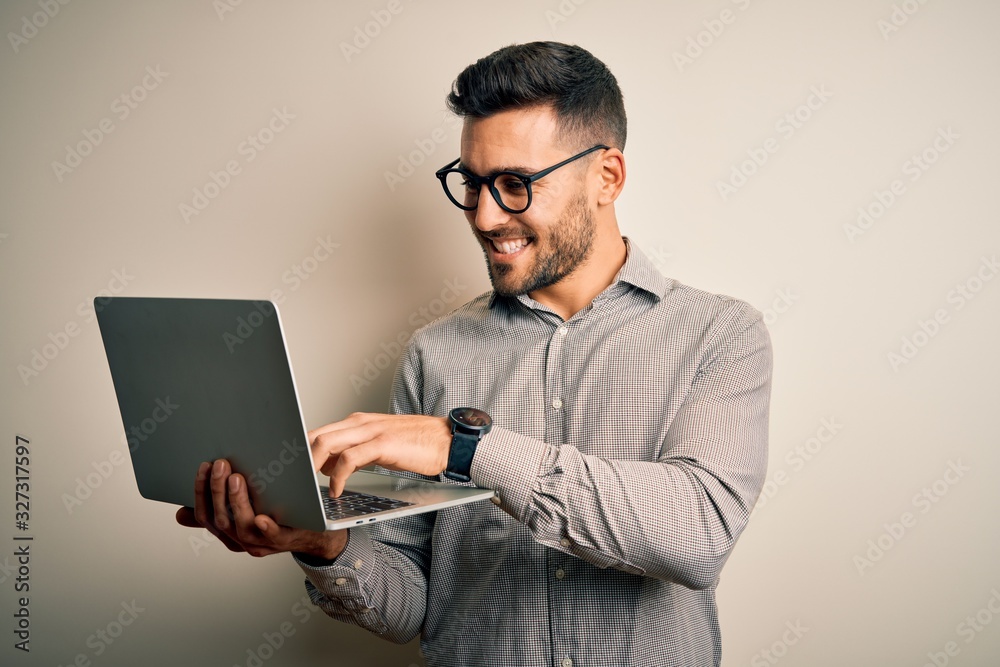 Young business man wearing glasses working using computer laptop with a happy face standing and smiling with a confident smile showing teeth Young business man wearing glasses working using computer laptop with a happy face standing and smiling with a confident smile showing teeth