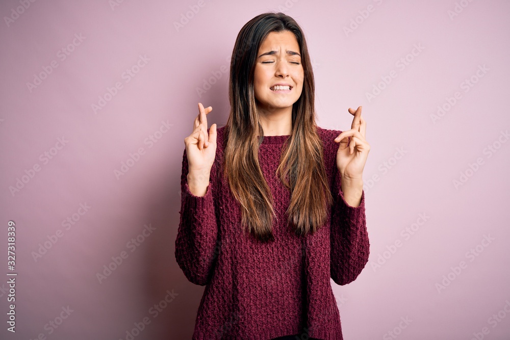 Young beautiful girl wearing casual sweater over isolated pink background gesturing finger crossed smiling with hope and eyes closed. Luck and superstitious concept. Young beautiful girl wearing casual sweater over isolated pink background gesturing finger crossed smiling with hope and eyes closed. Luck and superstitious concept.