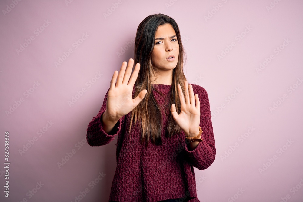 Young beautiful girl wearing casual sweater over isolated pink background Moving away hands palms showing refusal and denial with afraid and disgusting expression. Stop and forbidden. Young beautiful girl wearing casual sweater over isolated pink background Moving away hands palms showing refusal and denial with afraid and disgusting expression. Stop and forbidden.