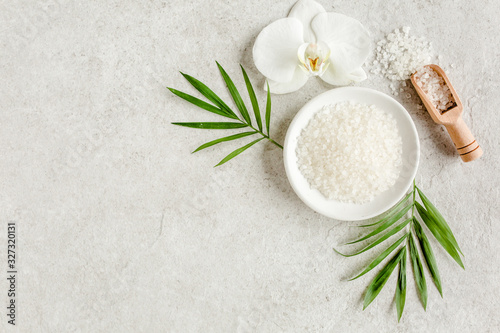 Spa treatment concept. Natural/Organic spa cosmetics products, sea salt and tropic palm leaves on gray marble table from above. Spa background with a space for a text, flat lay, top view.