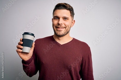 Young man with blue eyes drinking coffee from take away plastic bottle over isolated background with a happy face standing and smiling with a confident smile showing teeth