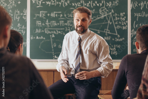 Cheerful bearded professor having a casual informal conversation with students during math seminar photo