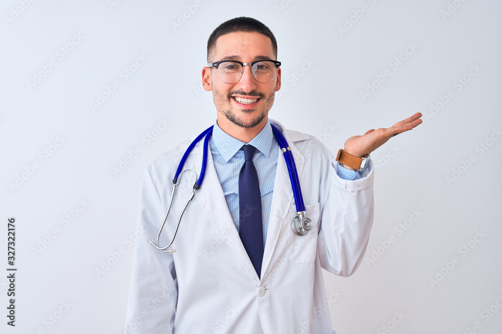 Young doctor man wearing stethoscope over isolated background smiling cheerful presenting and pointing with palm of hand looking at the camera.