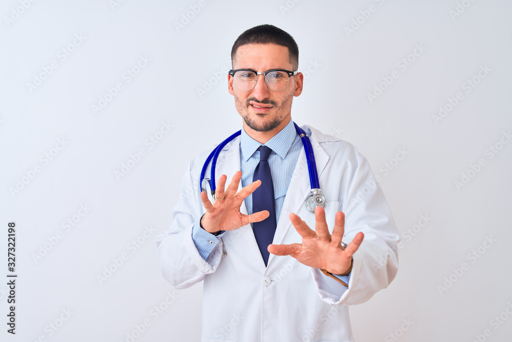 Young doctor man wearing stethoscope over isolated background disgusted expression, displeased and fearful doing disgust face because aversion reaction. With hands raised. Annoying concept. Young doctor man wearing stethoscope over isolated background disgusted expression, displeased and fearful doing disgust face because aversion reaction. With hands raised. Annoying concept.