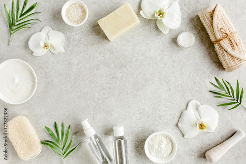 Spa skincare concept. Natural/Organic spa cosmetics products, sea salt and tropic palm leaves on gray marble table from above. Spa background with a space for a text, flat lay, top view.
