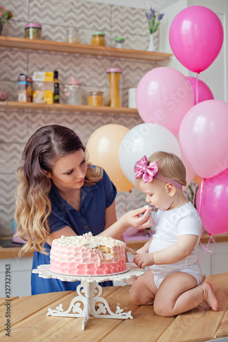 mother and daughter on the table with a birthday cake and balloons