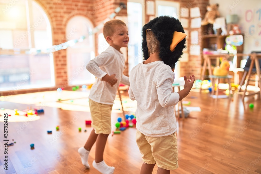 Obraz premium Adorable blonde twins playing wearing monkey mask around lots of toys at kindergarten