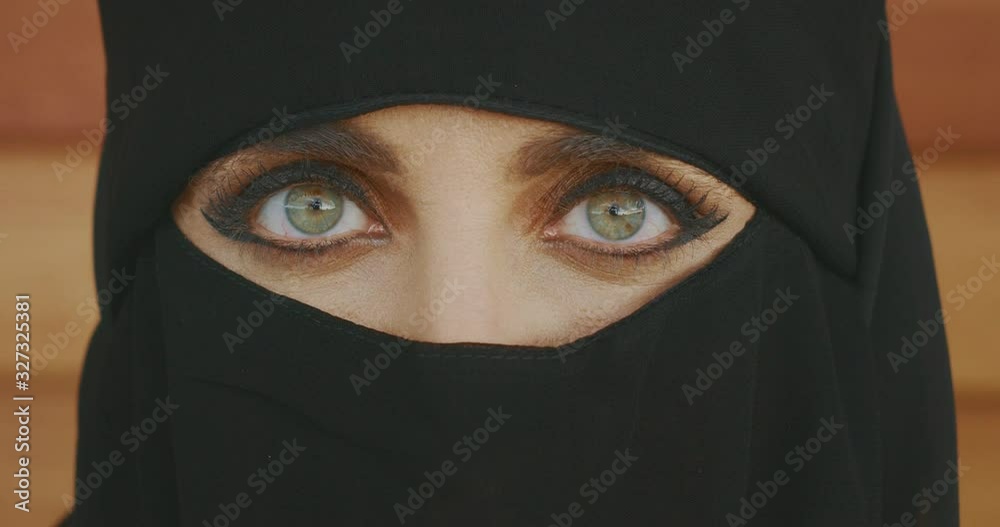 Portrait of a muslim woman wearing traditional black niqab showing only her green eyes, middle east culture Portrait of a muslim woman wearing traditional black niqab showing only her green eyes, middle east culture