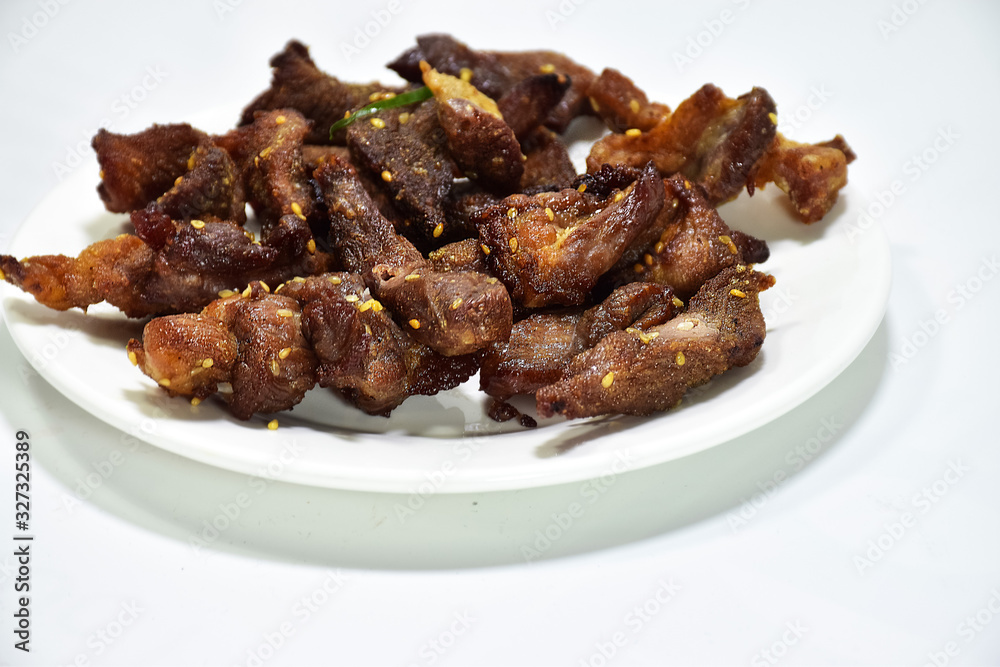 Marinated pork with sesame sauce, mixed grill skewers cooked in a white plate on a white background.