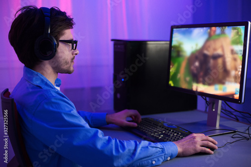 Gamer Playing Games Sitting At PC At Home At Night
