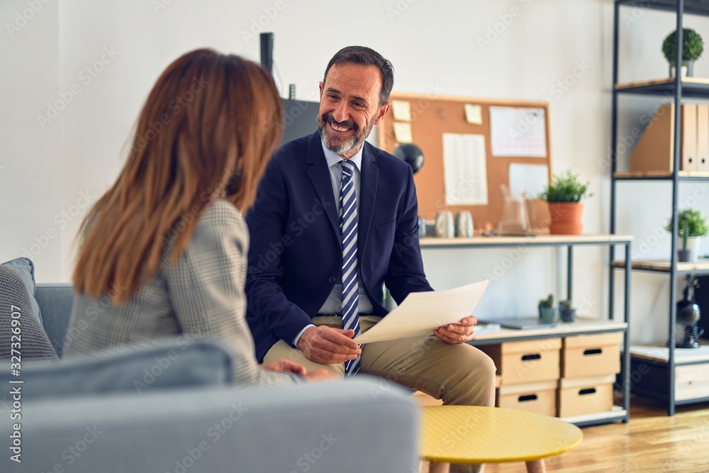 Two middle age business workers smiling happy and confident. Working together with smile on face holding documents at the office Two middle age business workers smiling happy and confident. Working together with smile on face holding documents at the office