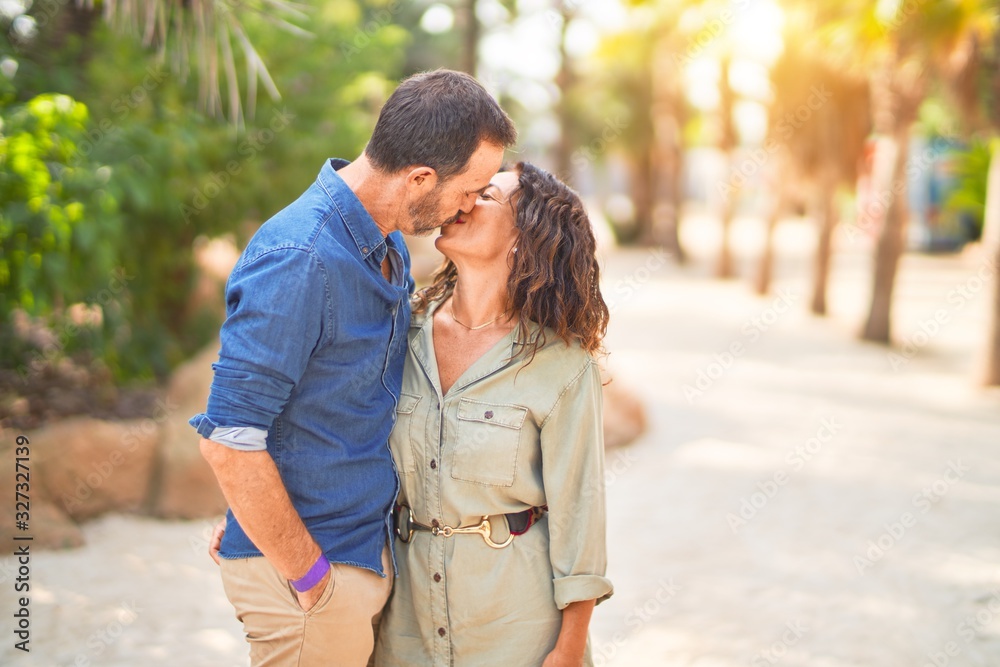 Middle age beautiful couple smiling happy and confident at town park. Standing with smile on face hugging and kissing Middle age beautiful couple smiling happy and confident at town park. Standing with smile on face hugging and kissing