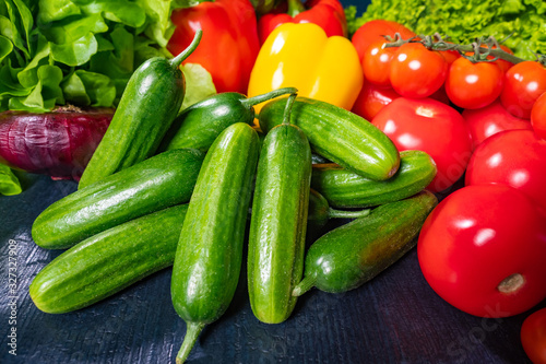 Fresh vegetables on dark background. On the table are cucumbers, tomatoes and peppers. Ingredients for fresh salad. Vegetarianism. A raw food diet. Vegetables contain vitamins.