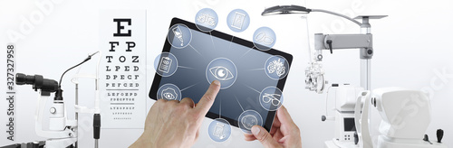 hands touch screen of digital tablet with ophthalmologist and optometrist icons symbols, ophthalmology and optometry equipment on background photo
