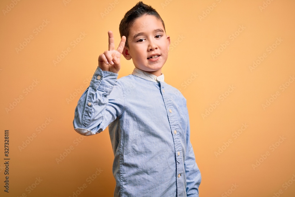 Young little boy kid wearing elegant shirt standing over yellow isolated background showing and pointing up with fingers number two while smiling confident and happy. Young little boy kid wearing elegant shirt standing over yellow isolated background showing and pointing up with fingers number two while smiling confident and happy.